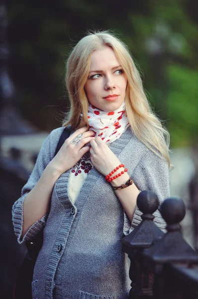 Schöne blonde Frau, die nachts in der Stadt steht, in einem weißen Kleid und einem Pullover am Halstuch, bescheiden und schüchtern, — Stockfoto