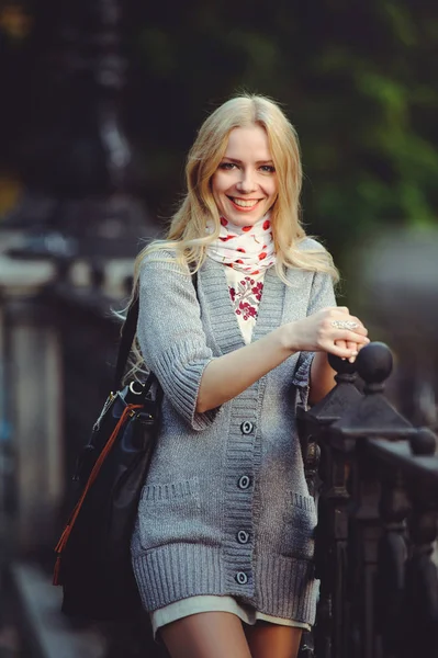 Mooie blonde vrouw permanent in de stad 's nachts gekleed in een witte jurk en een trui op haar hals sjaal, bescheiden en verlegen, — Stockfoto