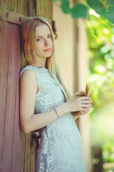 Atrakcyjne skromna młoda blond kobieta na czerwonym tle drewniane malowane jej włosy w różowe paski paski, w niebieskiej sukience nieśmiały i ciekawy — Zdjęcie stockowe