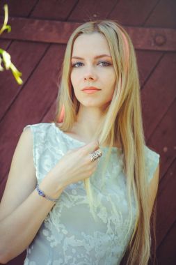 Çekici mütevazı genç sarışın kadın kırmızı ahşap zemin üzerine pembe çizgili çizgili, mavi elbiseli utangaç ve meraklı saçları boyalı