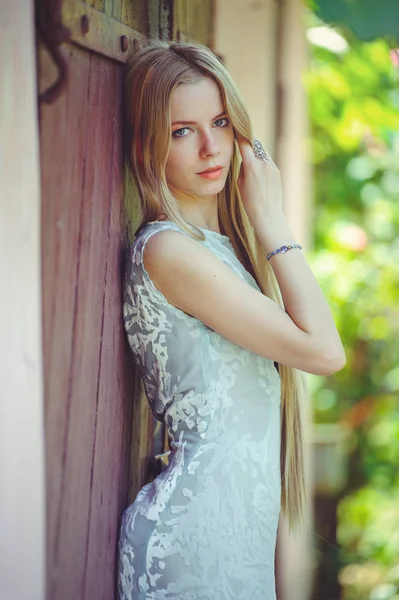Привлекательная скромная молодая блондинка на красном деревянном фоне ее волосы окрашены в розовую полосатую полоску, в голубое платье застенчиво и любознательно — стоковое фото