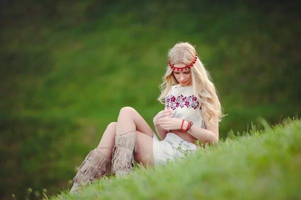 温柔的金发女郎坐在草地上 穿着天然的绣衣绷带在她的头上 在绿色的背景时尚和舒适 广告的概念 对自然的热爱 文本位置 — 图库照片