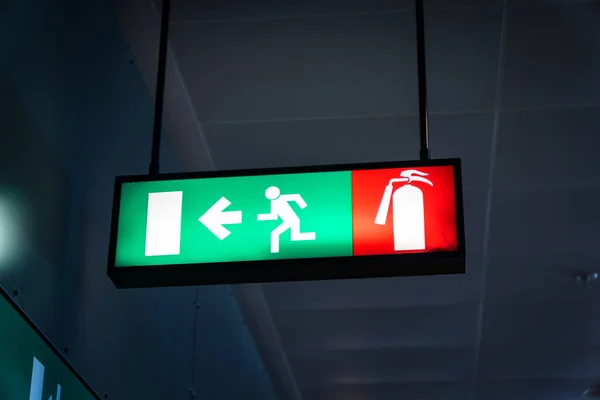 Emergency fire exit sign glowing green at airport