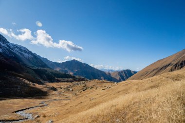 Güneşli bir sonbahar gününde nehir ve dağlarla Juta yürüyüş yolu - Kafkasya dağlarında popüler yürüyüş, Kazbegi bölgesi, Gürcistan.