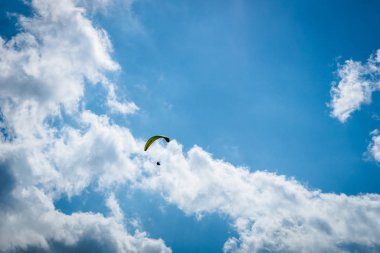 Yazın beyaz bulutlarla mavi gökyüzünde yamaç paraşütü yapıyor