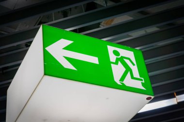 Havaalanındaki karartılmış arka planda acil yangın çıkışı işareti parlıyor.