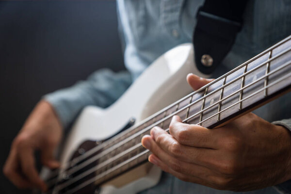 musician playing bass guitar finger style, closeup and selective focus- musical instrument for jazz, rock, blues, funk, hip hop music