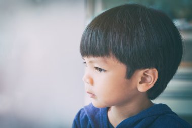 Asyalı çocuk cidden pencereden dışarı bakıyor 