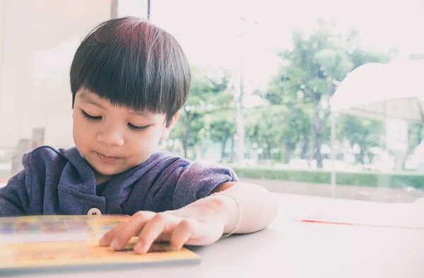 Azjatycki chłopiec czyta książki edukacyjne gry. — Zdjęcie stockowe