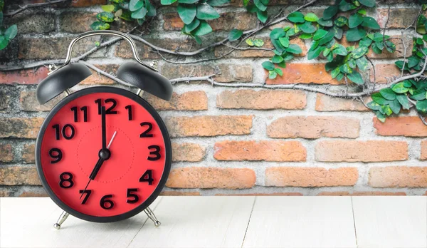 Alarma roja Reloj en mesa con fondo de planta de ladrillo —  Fotos de Stock