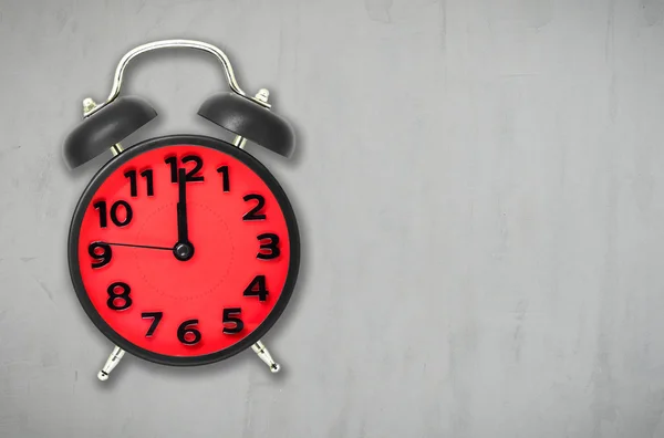 Ρολόι ξυπνητήρι κόκκινο μεσημεριανού σε φόντο γκρι τσιμέντο με αντίγραφο χώρου. — Φωτογραφία Αρχείου