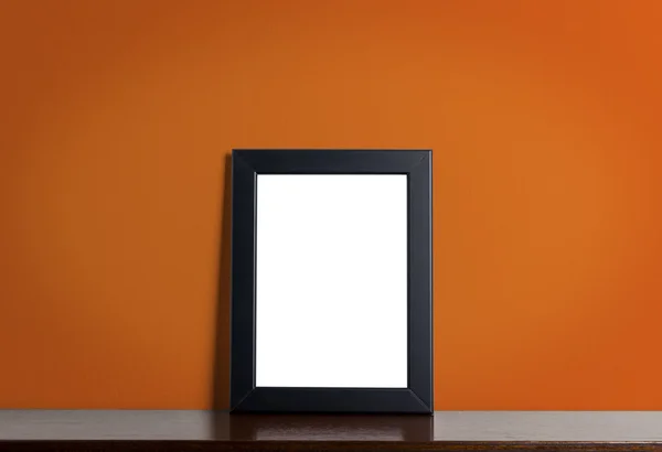 Чорна фоторамка на помаранчевому фоні стіни . — стокове фото