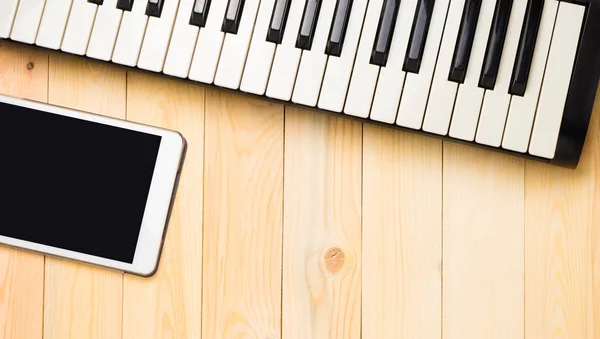 Ahşap arka plan üzerinde tablet ile müzikal klavye — Stok fotoğraf