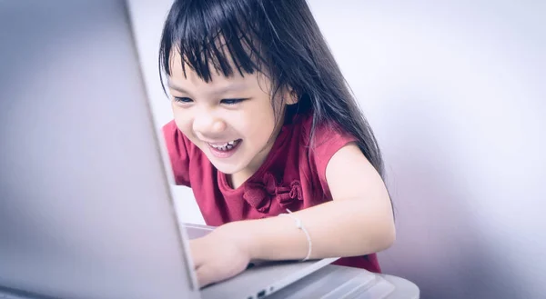 Chico asiático es disfrutar de la adicción de la computadora y de Internet. Chica japonesa está jugando inconscientemente que es perjudicial para ella. Niña se está divirtiendo con el ordenador . —  Fotos de Stock