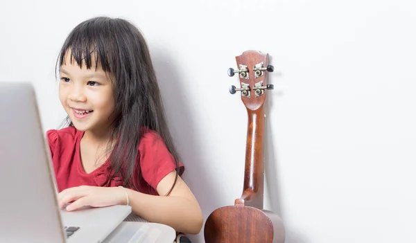Küçük müzisyen çocuk onun müzik bir dizüstü bilgisayarda çalışıyor. Asyalı çocuk müzik Not internette arıyor. Japon kız online gitar müzik kursu alıyor.