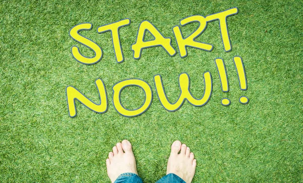 Start now concept text with human foot on green grass