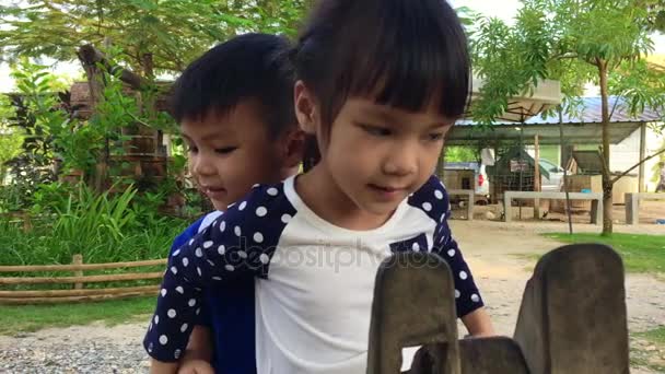 Азиатский брат и сестра едут на деревянных лошадиных качелях — стоковое видео
