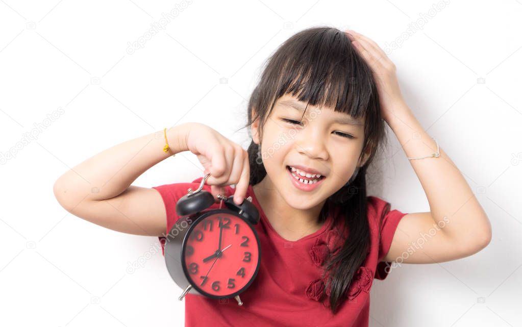 Lazy Asian girl holding her alarm clock looking upset because the alarm clock ring and she doesn't want to wake up.