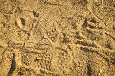 Ayakkabı ve ayak adımları pompa kumlu zeminde.