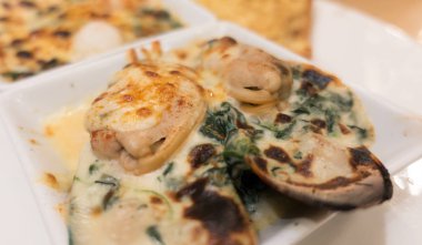 Ispanak ve peynirli beyaz tabakta midye