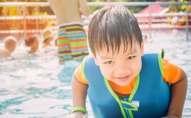 Asyalı çocuk havuzunda can yeleği ile Yüzme
