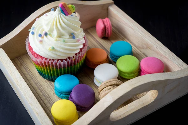 Bunte Macaron-Plätzchen und Cupcake auf Holzblech — Stockfoto