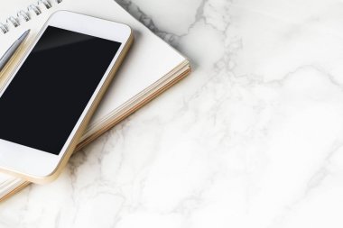 Boş akıllı telefon perde kopya alanı ile mermer masa üstünde boş defter ile