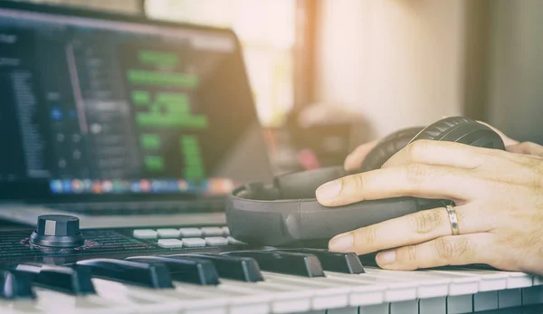 Músico segurando um fone de ouvido no teclado de música em casa mmsuic estúdio — Fotografia de Stock