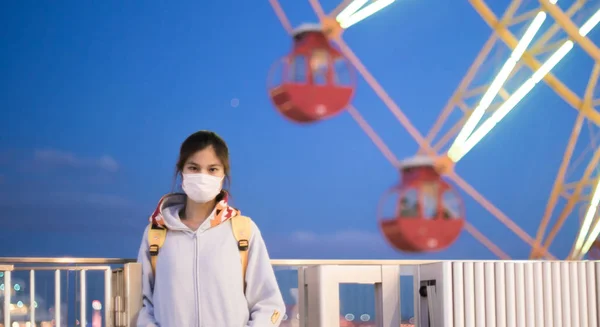 A masked teenager with ferris wheel backgorund — Stock Photo, Image