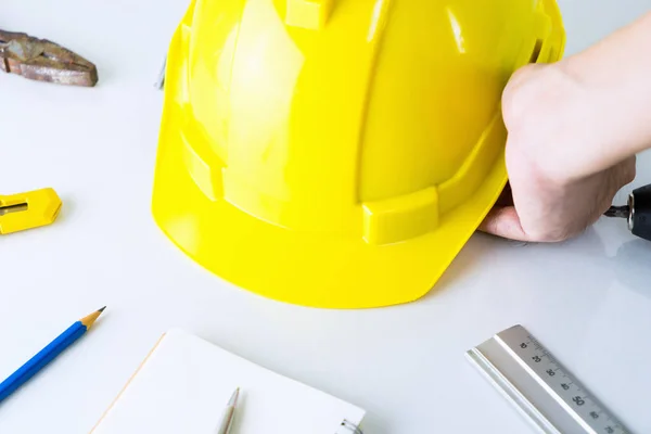 Byggnadsarbetare är att plocka upp säkerhet hjälm från verktyget skrivbord — Stockfoto