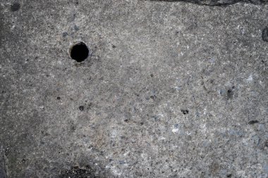 Üstte bir delik ile beton zemin yol yüzeyi.