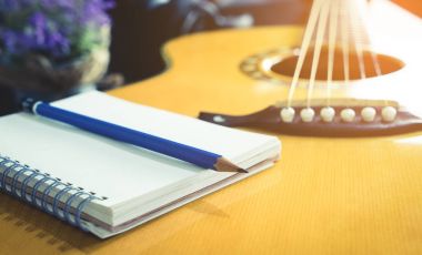 Gitarist ve söz yazarı ile boş defter ve kalem şarkı müzik yazmak için