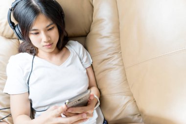 İyi deri kanepe smartphone kulaklık müzik dinlerken ile şirin Asyalı kız