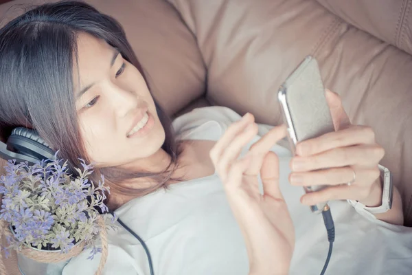 Belle asiatique fille est écouter de la musique sur smartphone — Photo