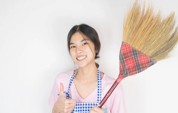 Asiatische junge Hausfrau ist halten ein Besen isoliert auf weiß — Stockfoto