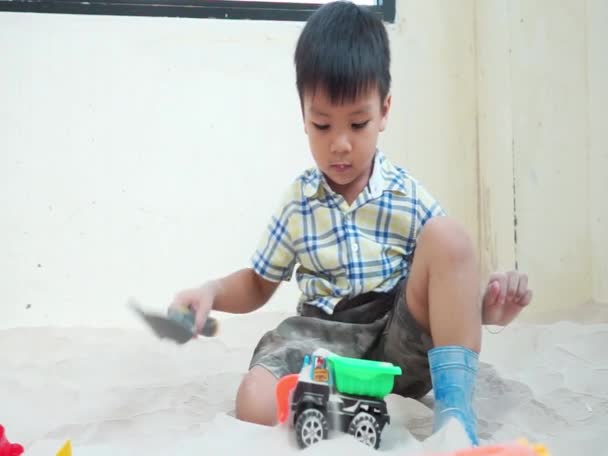 Asian boy is playing with educational toy in sandbox — Stock Video