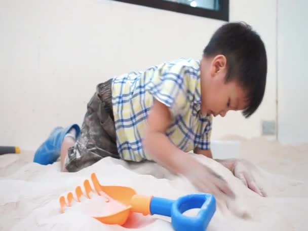 Asiatische junge ist spielen in sandbox mit bunten Spielzeug. — Stockvideo