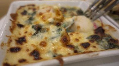 Fırında ıspanak ve peynir yemek yemek için çatal kullanarak