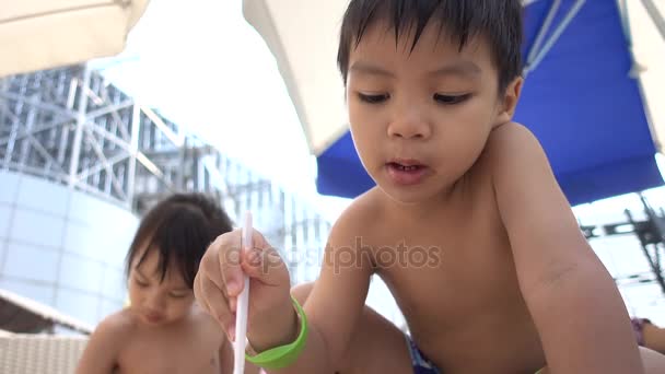 Asiatico bambino è mangiare francese patatine fritte su il spiaggia — Video Stock