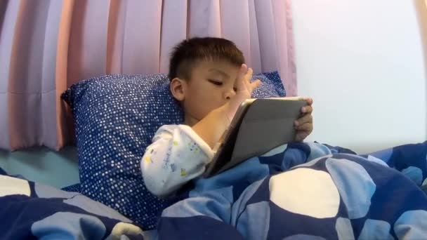 Asiático niño jugando juego en la tableta antes de ir a dormir — Vídeo de stock