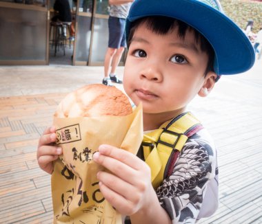 Asyalı çocuk Asakusa'nın ünlü Melonpan ekmek yiyor.