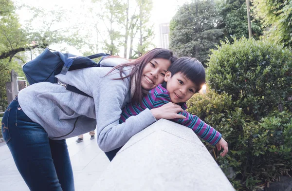 Asiático madre es holding su hijo en un rock puente con amor y divertido — Foto de Stock