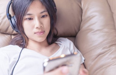 Şirin Asyalı kız müzik dinlemek üstünde hareket eden telefon olduğunu