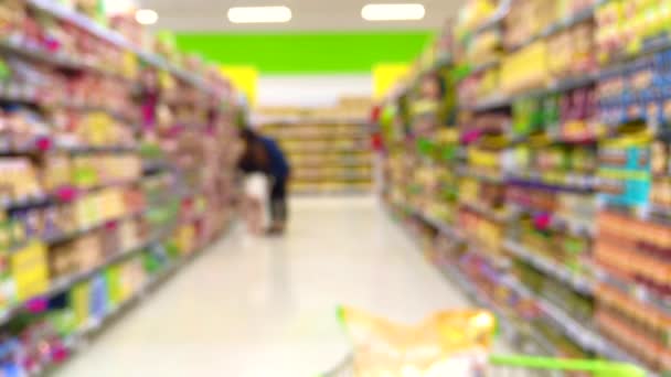 Rozmazaný záběr spotřebitelů v supermarketu z nákupního košíku 