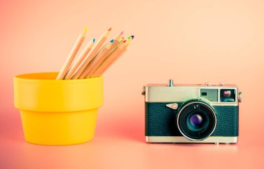 Fotoğraf makinesi ile fotoğrafçı ve Tasarımcısı konsepti için pembe bir arka plan üzerinde renkli pastel kalemler