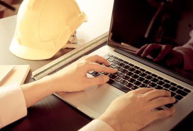 Yüklenici Yöneticisi bilgisayar ofis masaları ile mühendis kask üzerinde çalışıyor