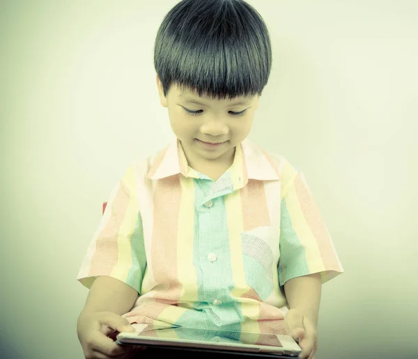Pequeño chico asiático está disfrutando el uso de la tableta — Foto de Stock