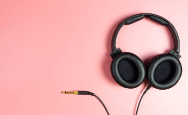 Pembe kopya alanı üzerinde siyah müzik kulaklık