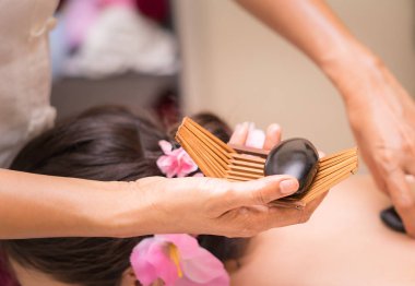 Kadınlar için sağlık ve tıp kavramı üzerinde siyah sıcak taş Spa Masaj terapisti yatıyor