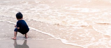 Asyalı çocuk dalga ile oynama ve sahilde kum